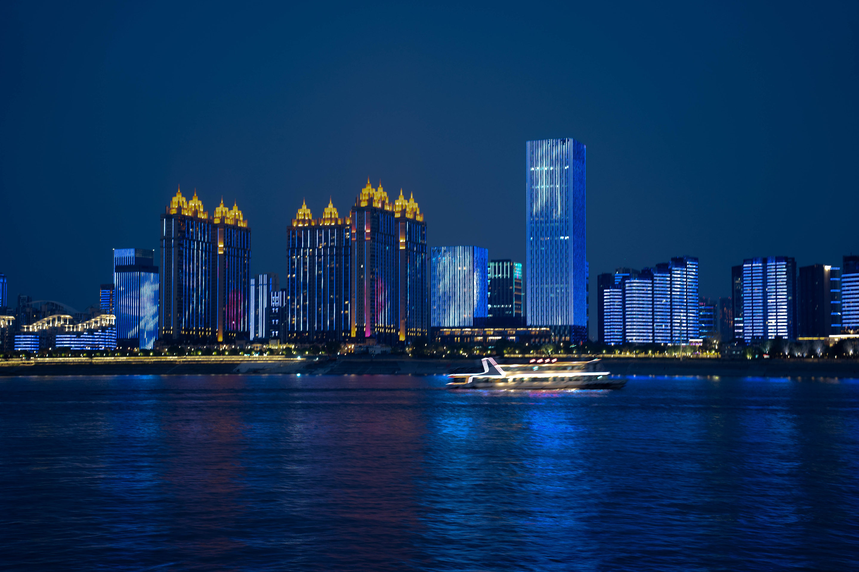 City skyline lit blue at nightfall, reflected in the river