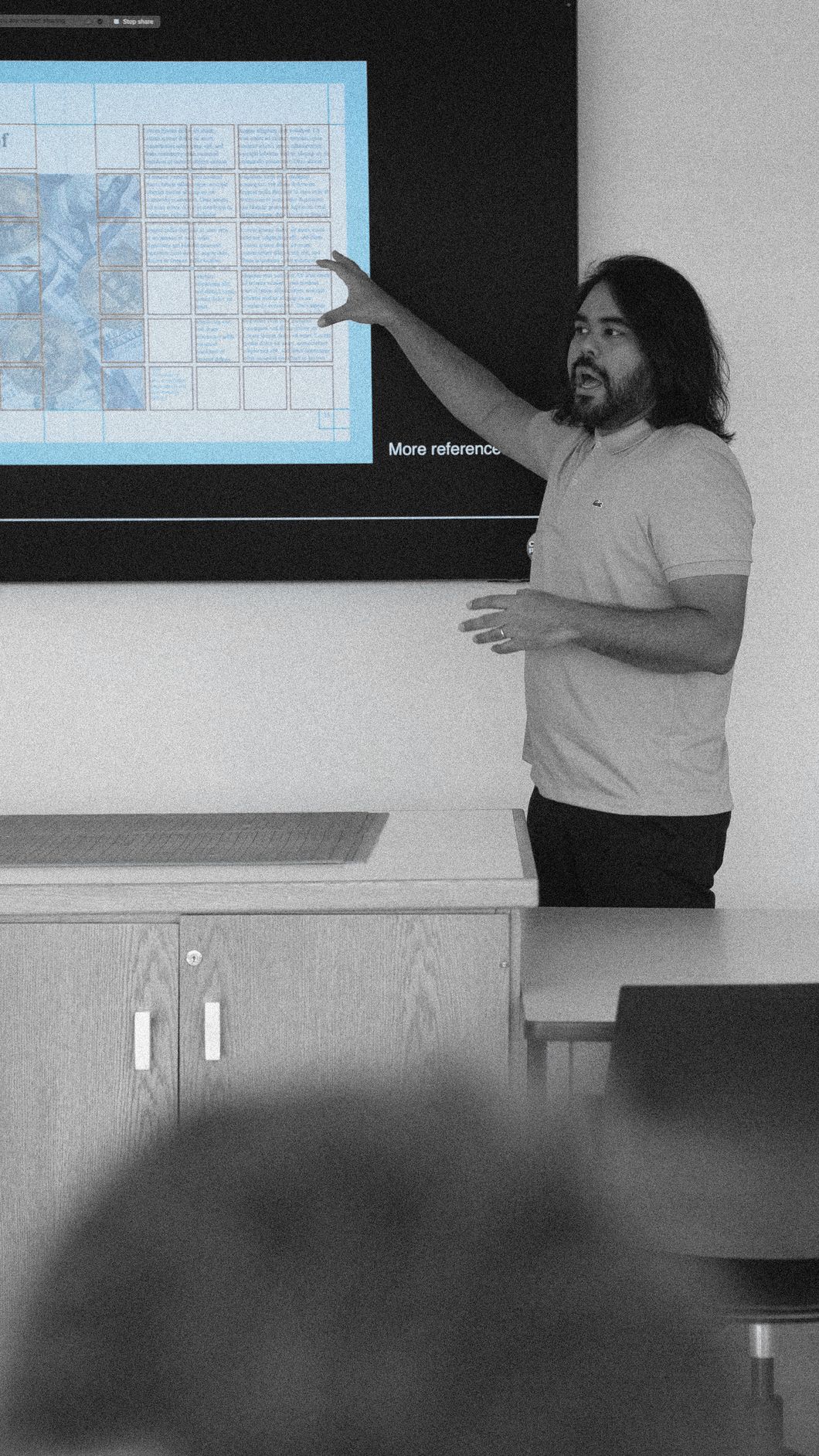Design in Discussion, 1:00 PM: an instructor points at a page grid on a large screen