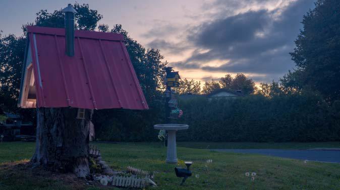 A tree house with a red roof at dusk